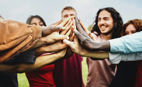 Joyful group of multi-ethnic community of happy people having fun joining hands in the park