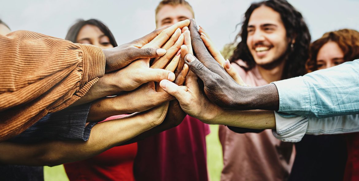 Joyful group of multi-ethnic community of happy people having fun joining hands in the park